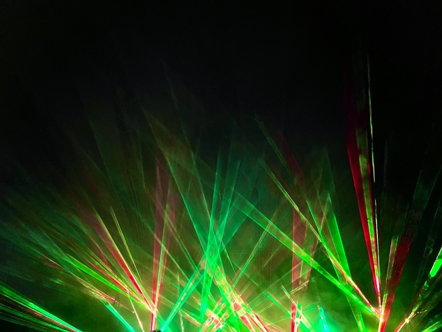 ホノルルのナイトショーで夜空を彩る鮮やかな緑と赤のレーザービームの演出。