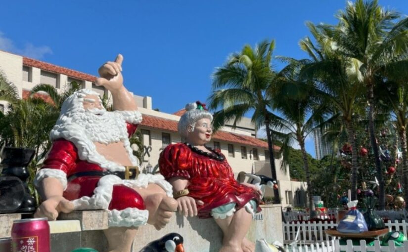 ホノルル・シティ・ライツのサンタ夫妻の像。シャカサインを掲げるサンタと、赤いドレスのミセス・クロース。