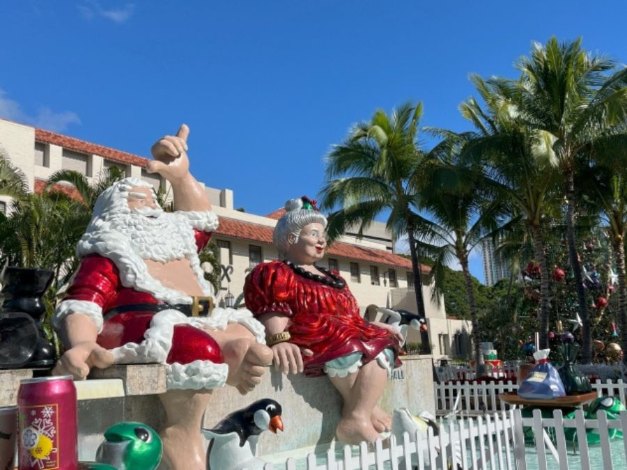 ホノルル・シティ・ライツのサンタ夫妻の像。シャカサインを掲げるサンタと、赤いドレスのミセス・クロース。